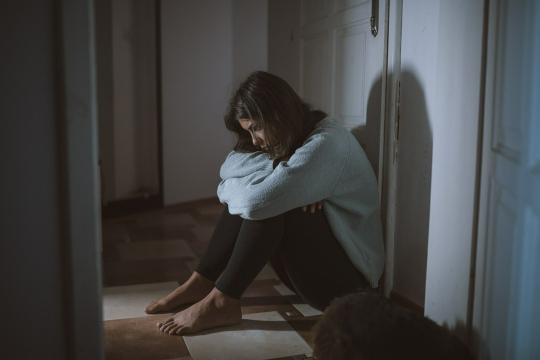 kobieta w depresji siedząca pod drzwiami w mieszkaniu